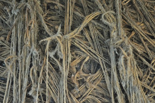 Close-up of intertwined natural fibers, showcasing a textured, earthy pattern with knots and strands.