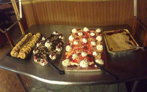 A dessert table featuring cookies, layered cake with whipped cream, and a fruit-topped dessert in trays.
