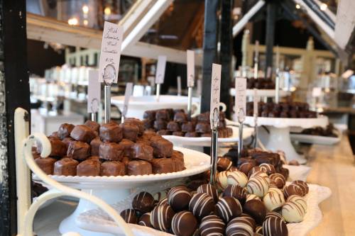 A display of assorted chocolates on elegant white platters in a cozy shop setting.