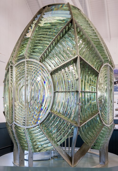 A large, intricate glass lens structure with a metallic frame, showcasing a unique geometric design.