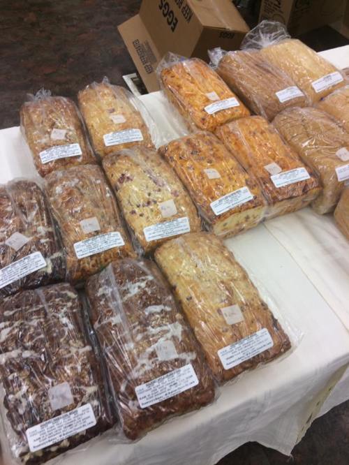 A table displaying various loaves of bread, each wrapped and labeled, in different colors and textures.