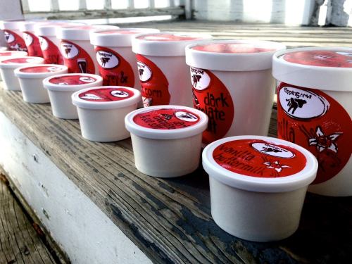 A row of various ice cream containers with colorful labels on a wooden surface.