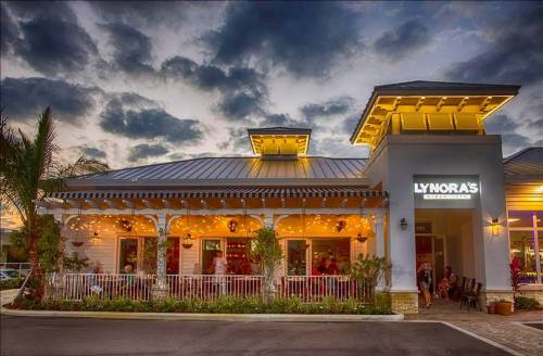 A charming restaurant exterior at dusk, featuring outdoor seating, warm lights, and a welcoming atmosphere.