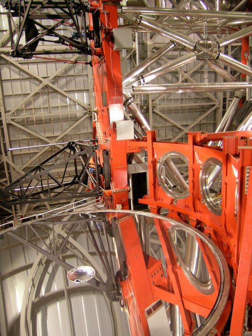 Close-up of a large telescope's reflective surface and intricate metal framework, showcasing its complex design.