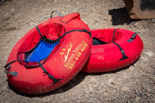 Two red inflatable tubes resting on a rocky surface, one with a blue interior, ready for tubing activities.