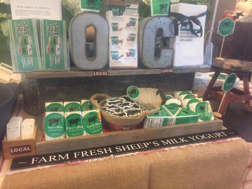 Display of local sheep's milk yogurt products with decorative letters and signage promoting freshness and local sourcing.