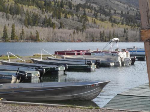 Boats docked at a serene lake surrounded by trees and mountains on a clear day.