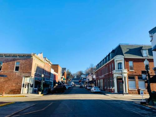 A quiet street scene in a small town, featuring brick buildings and clear blue skies.