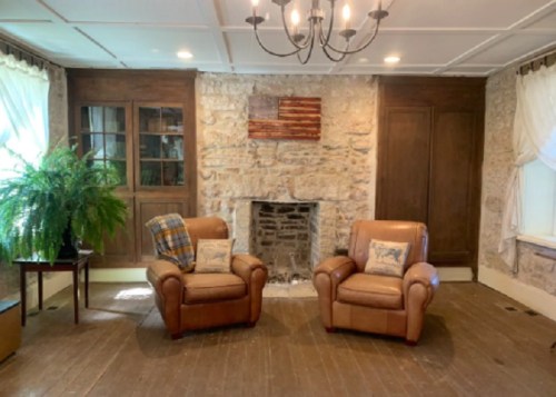 Cozy living room with two leather chairs, a stone fireplace, and an American flag art piece on the wall.