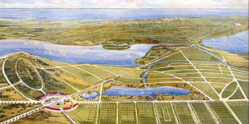 Aerial view of a landscape with water bodies, fields, and a planned layout of roads and buildings.
