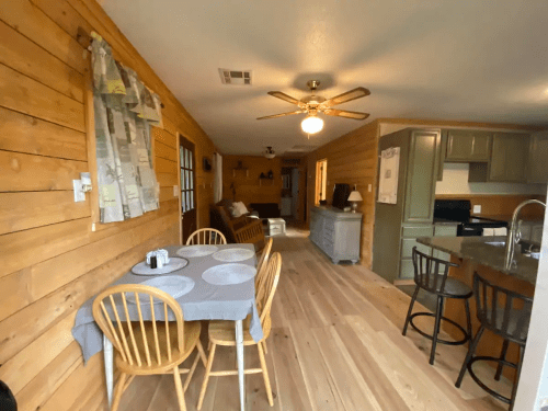 Cozy interior of a wooden cabin featuring a dining table, living area, and kitchen with modern appliances.