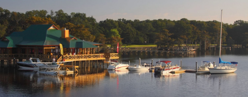 A scenic waterfront view featuring a colorful dockside restaurant and several boats moored in calm waters.