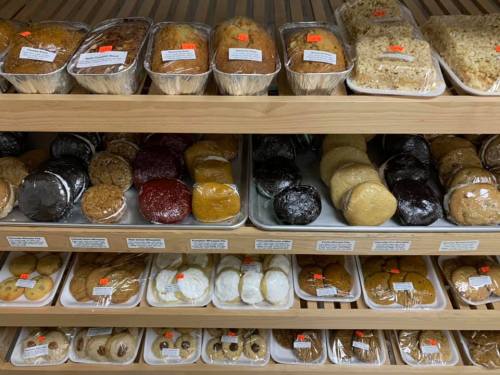 A display of various baked goods, including cookies, cakes, and pastries, neatly arranged on wooden shelves.