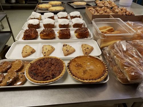 A variety of baked goods on a table, including pies, cookies, muffins, and pastries in a kitchen setting.