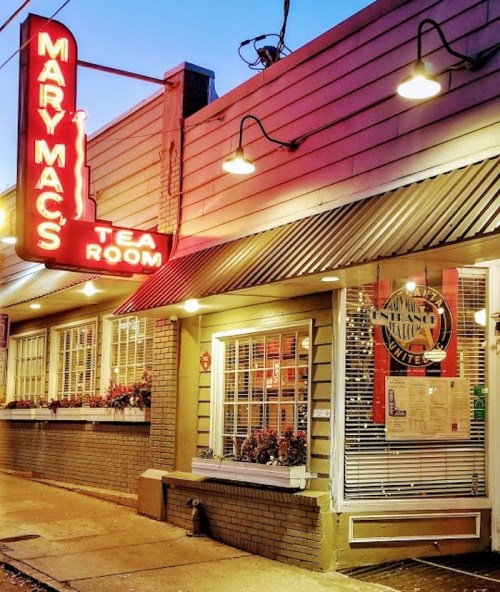 Exterior of Mary Mac's Tea Room at dusk, featuring a bright neon sign and warm, inviting lights.