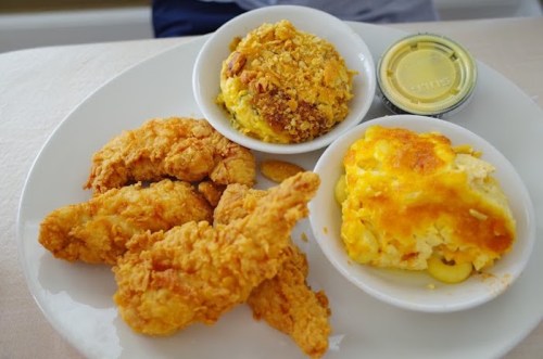 A plate with crispy fried chicken, macaroni and cheese, and a baked dish topped with breadcrumbs.