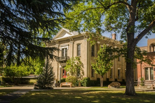 A historic building surrounded by trees and greenery, featuring a classic architectural style and a welcoming entrance.