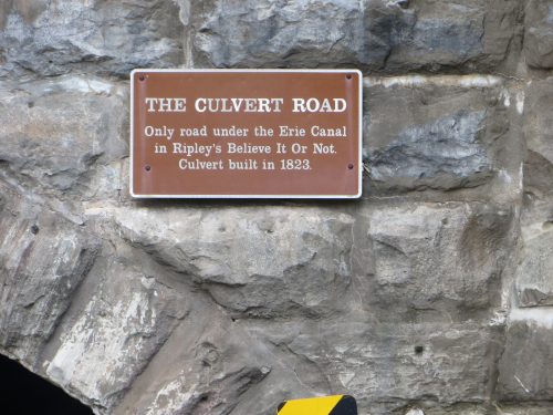 Sign on a stone wall reading about the Culvert Road under the Erie Canal, built in 1823.