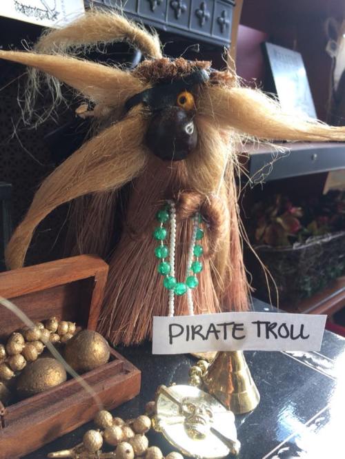 A whimsical pirate troll with long hair, a necklace, and a treasure chest, displayed on a shelf.