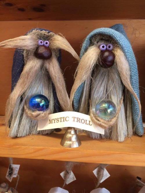 Two whimsical troll figurines with long beards, wearing blue and gray hats, each holding a blue orb, labeled "MYSTIC TROLL."