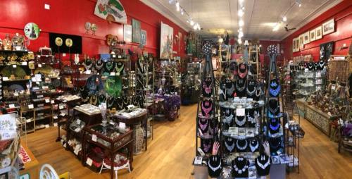 A vibrant store interior filled with various jewelry, decorative items, and art, featuring red walls and wooden flooring.