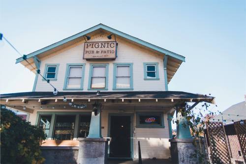 A charming pub with a sign reading "Pignic Pub & Patio," featuring string lights and a welcoming entrance.