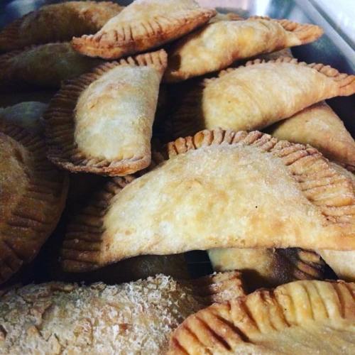 A close-up of golden-brown empanadas piled together, showcasing their flaky crusts and crispy edges.