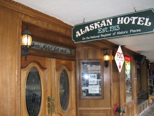 Entrance of the Alaskan Hotel, established in 1913, featuring wooden doors and historic signage.