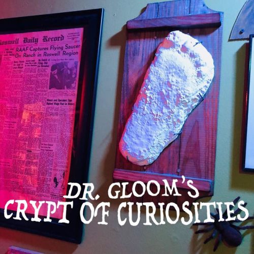 A wall display featuring a newspaper clipping and a white, textured object in a dimly lit room labeled "Dr. Gloom's Crypt of Curiosities."