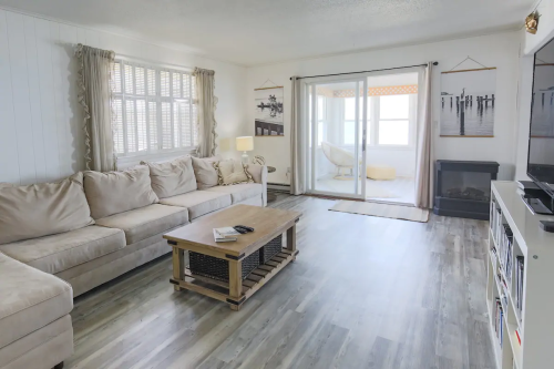 Cozy living room with a beige sectional sofa, wooden coffee table, and sliding doors leading to a sunroom.