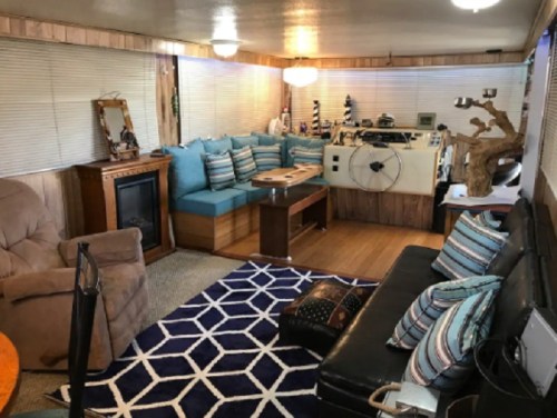 Cozy living room with blue seating, a wooden table, and a decorative rug, featuring a fireplace and natural decor.