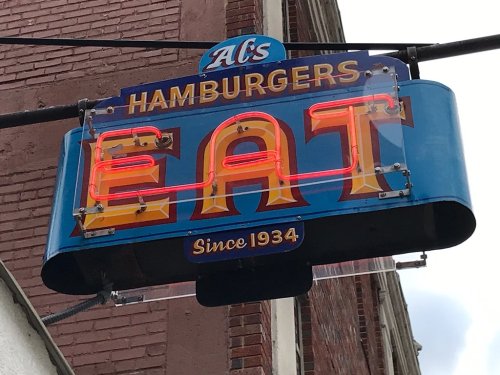 Neon sign for Al's Hamburgers, featuring the word "EAT" prominently, established in 1934.