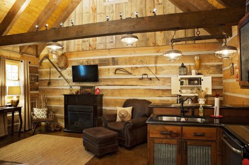 Cozy cabin interior with wooden walls, a fireplace, a comfortable chair, and rustic decor. Warm and inviting atmosphere.