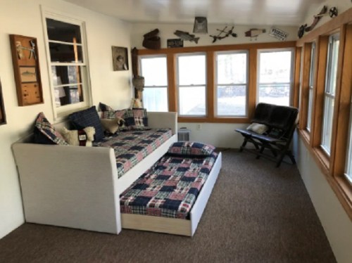 Cozy sunroom with a daybed, patterned cushions, and large windows letting in natural light.