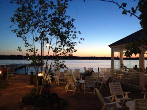 A serene lakeside view at dusk, featuring outdoor seating and a soft blue and orange sky.