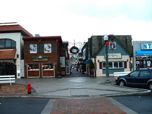 A charming street scene featuring shops with festive decorations and a cloudy sky overhead.