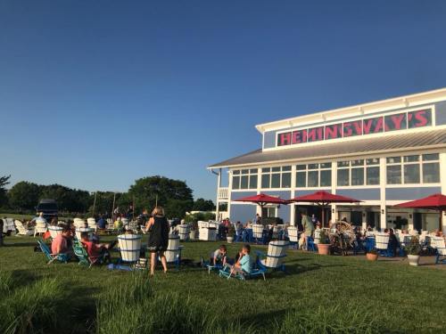 A lively outdoor scene at Hemingway's, featuring colorful chairs and people enjoying the sunny weather.