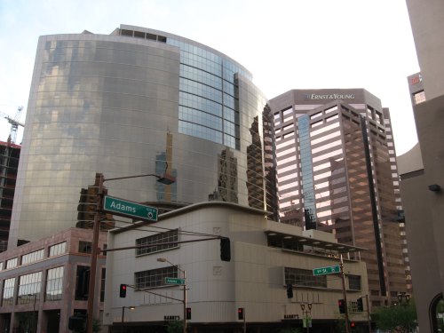 Modern skyscrapers with reflective glass facades, located at a city intersection with street signs visible.
