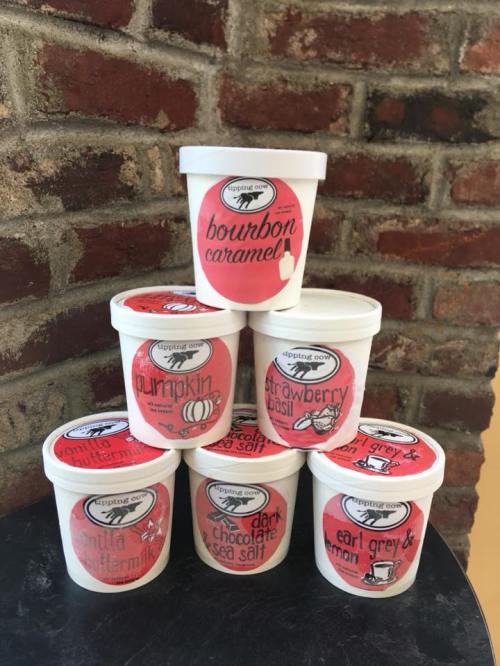 A stack of ice cream tubs with flavors: bourbon caramel, pumpkin, strawberry basil, buttermilk, dark chocolate sea salt, and earl grey & lemon.