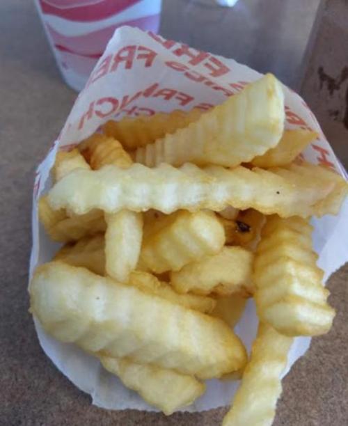 A serving of crinkle-cut French fries in a paper container.
