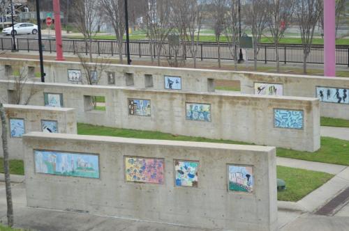 A park with concrete walls displaying colorful murals and artwork, surrounded by grass and trees.