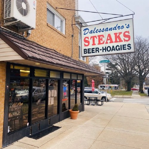 Exterior of Dalessandro's Steaks with a sign displaying "Steaks, Beer, Hoagies" on a cloudy day.