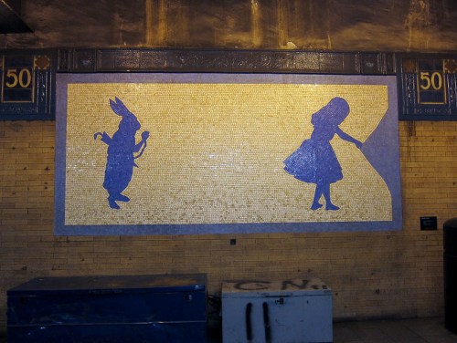 Mosaic mural featuring a rabbit and a girl, inspired by "Alice in Wonderland," on a subway wall.