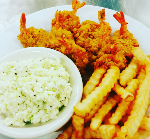 A plate of crispy fried shrimp, crinkle-cut fries, and a side of creamy coleslaw.