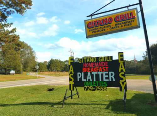 Sign for Gitano Grill advertising lunch plates, breakfast, po-boys, and pies, with a focus on omelettes and easy service.