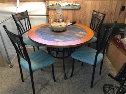 A round dining table with a mosaic top and four blue upholstered chairs in a cozy interior setting.