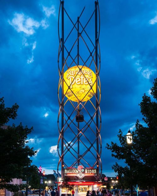 A brightly lit sign for "Parkey Pete's Balloon Rides" against a dramatic evening sky with clouds.