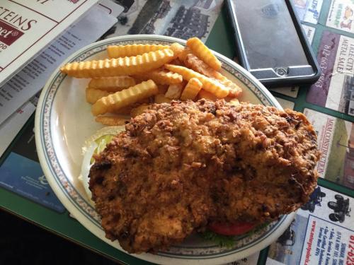 A plate of crispy fried chicken with lettuce and tomato, served alongside golden crinkle-cut fries.