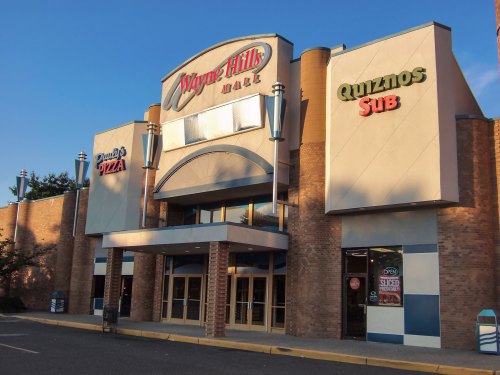 Exterior of Wayne Hills Mall featuring a Quiznos Sub and a pizza restaurant, with a clear blue sky above.