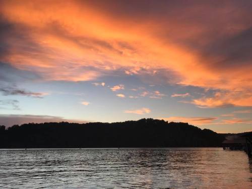 A serene lake at sunset, with vibrant orange and purple clouds reflecting on the water's surface.